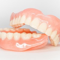Full set of glistening dentures on a white surface
