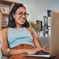 Woman smiling while working on laptop at home