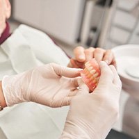 Man giving his dentures to his dentist