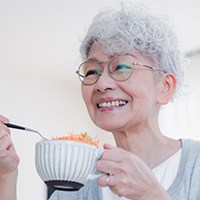 Woman with dentures smiling while eating
