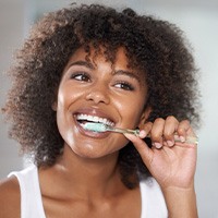 Woman smiling while brushing her teeth