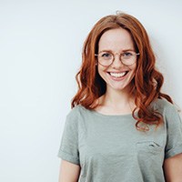 Red-haired woman with glasses smiling