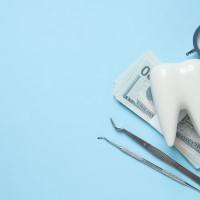 A clock, decorative tooth and money on a blue background