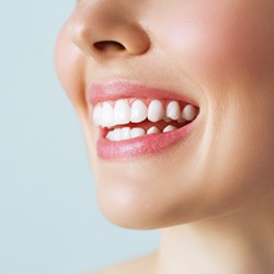 Nose-to-neck ¾ profile view of woman smiling with gray background