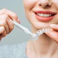 Woman applying whitening gel to custom-fitted applicator tray