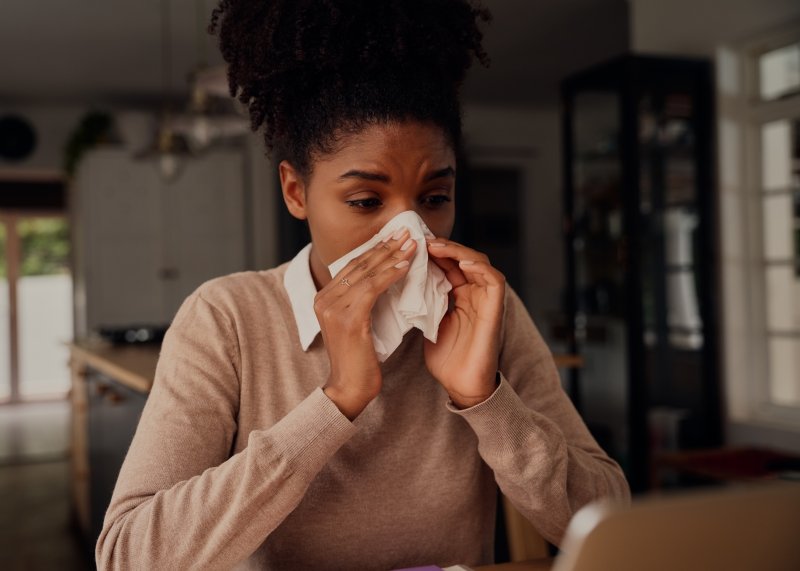 person suffering from seasonal allergies blowing nose