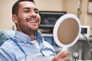 dental patient smiling and looking in a mirror